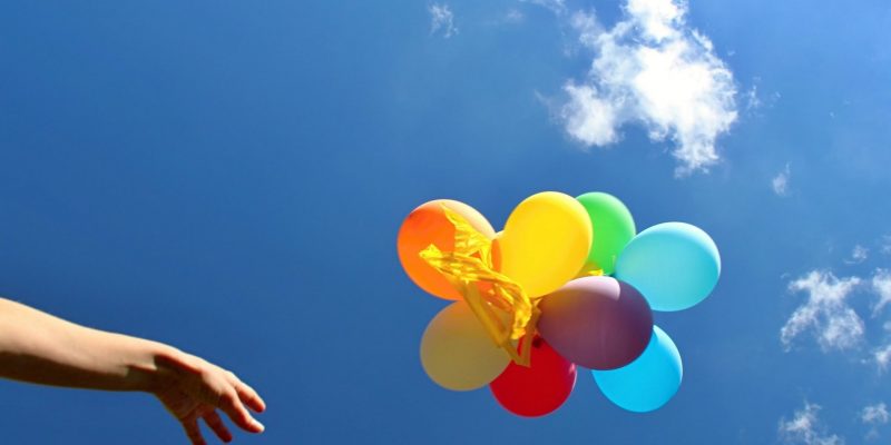 человек отпускает шарики в небо